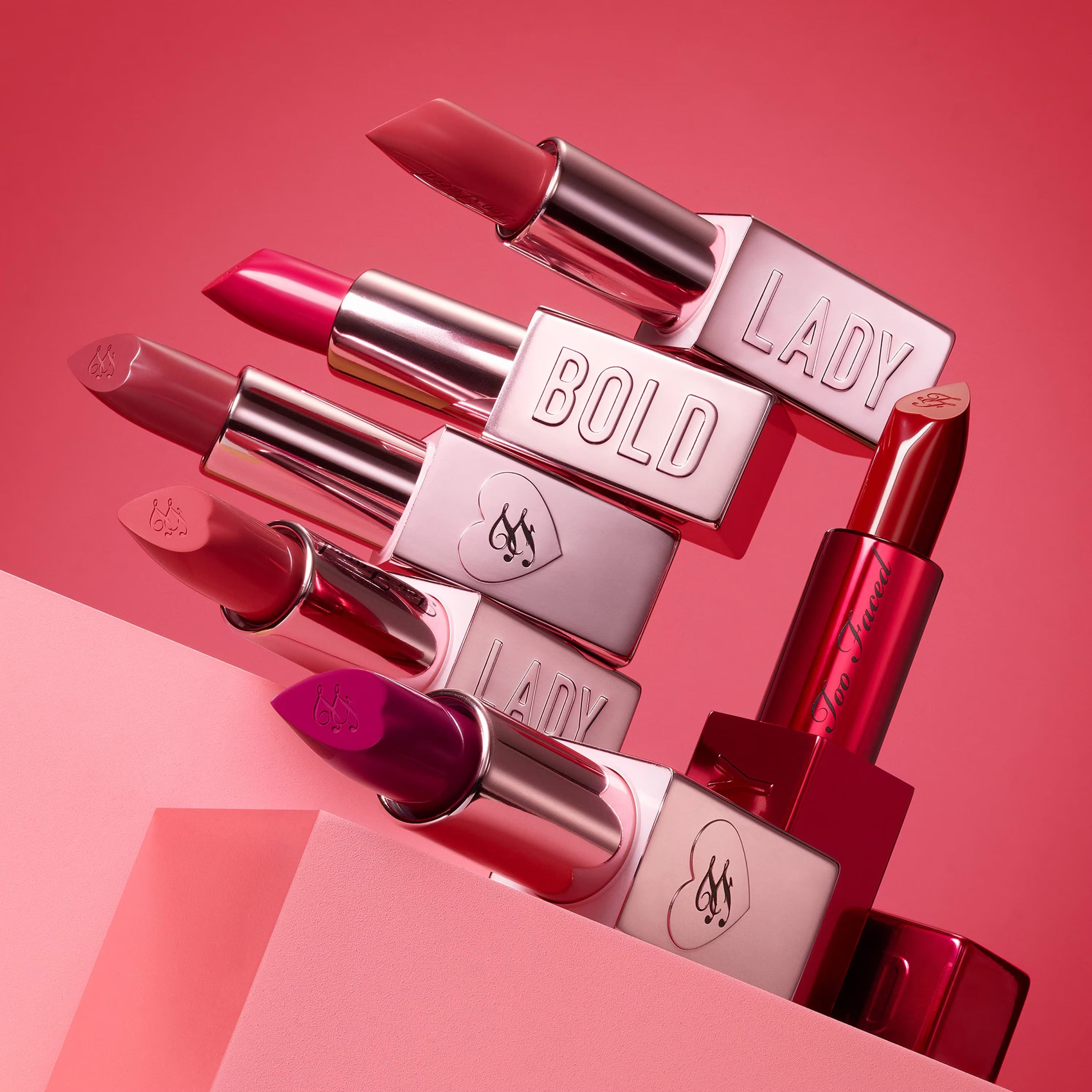 Too Faced Lady Bold Lipstick in various shades, featuring sleek packaging and vibrant colors, showcasing a beauty product for lips.