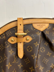 Louis Vuitton Monogram Tivoli GM bag with rounded leather handles, monogram canvas, and gold-tone hardware on a neutral background.