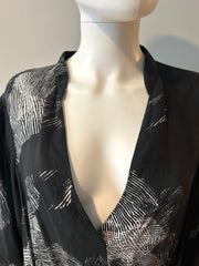 Raquel Allegra XL graphic print dress hanging on a wooden hanger, showcasing bold abstract patterns and flowing fabric.