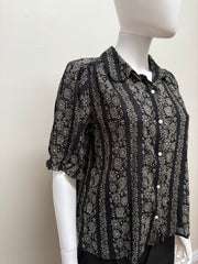 Light blue cotton blouse from The Great, featuring a classic collar and button-front design, displayed on a hanger.