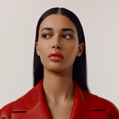 Hermès Silky Lipstick Shine in vibrant orange shade, glossy finish, showcasing the elegant lipstick tube and textured packaging.